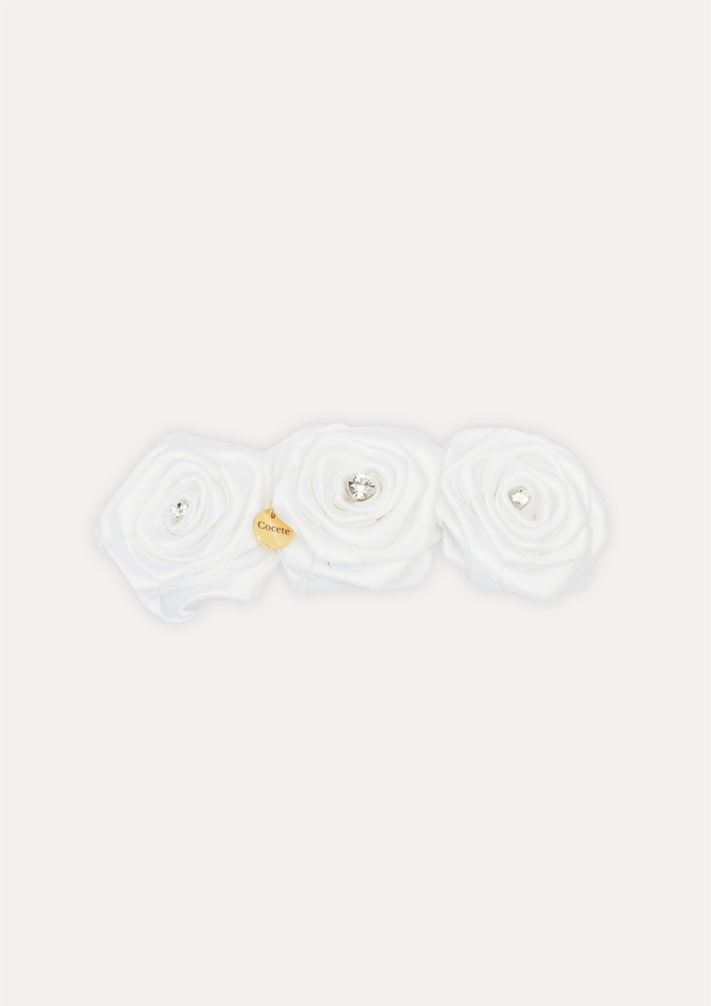 Handmade white triple fabric rose hair clip for girls, featuring crystal centers and a small gold COCETE brand charm.