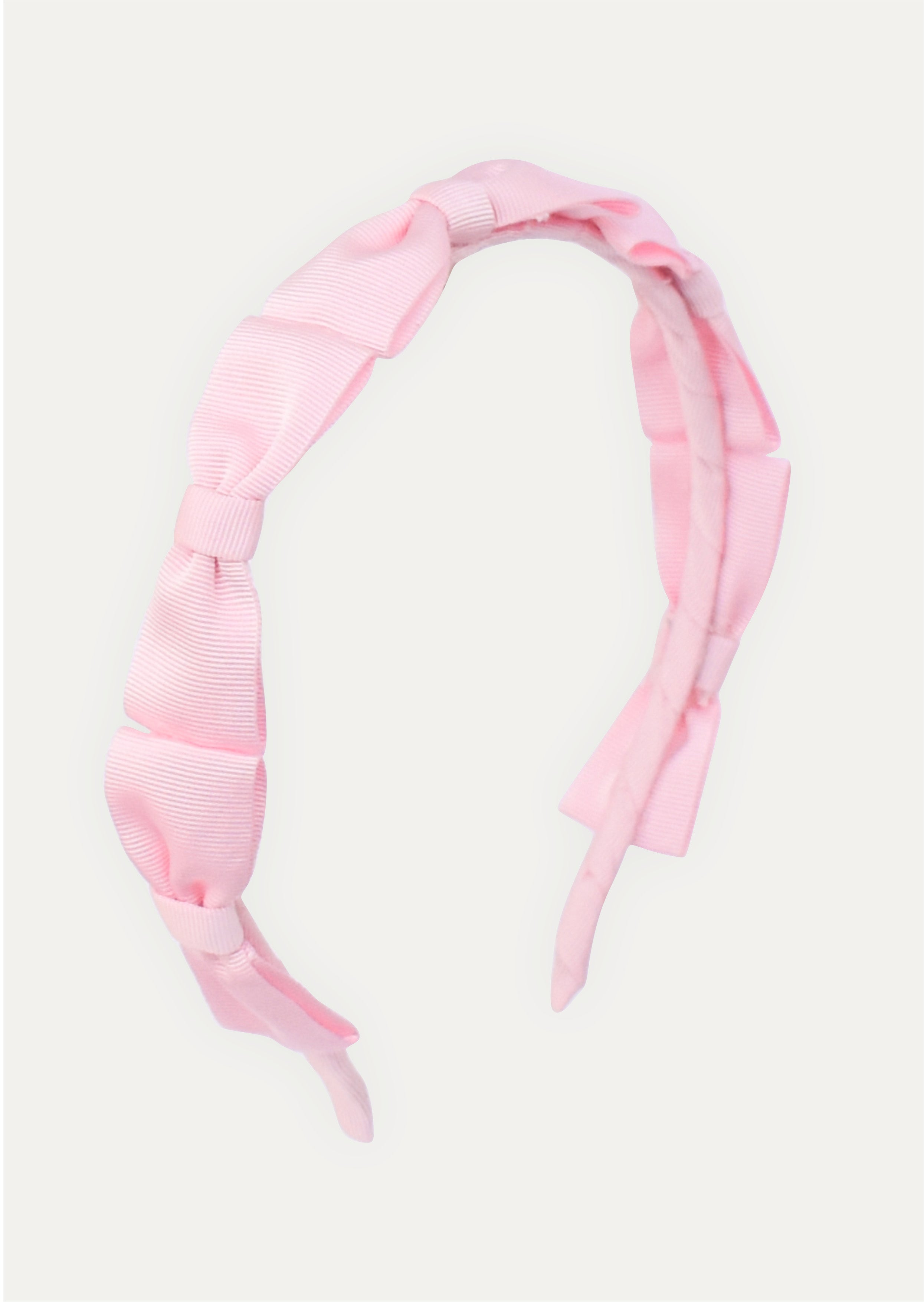 Handmade pink headband for girls featuring a series of small grosgrain ribbon bows.