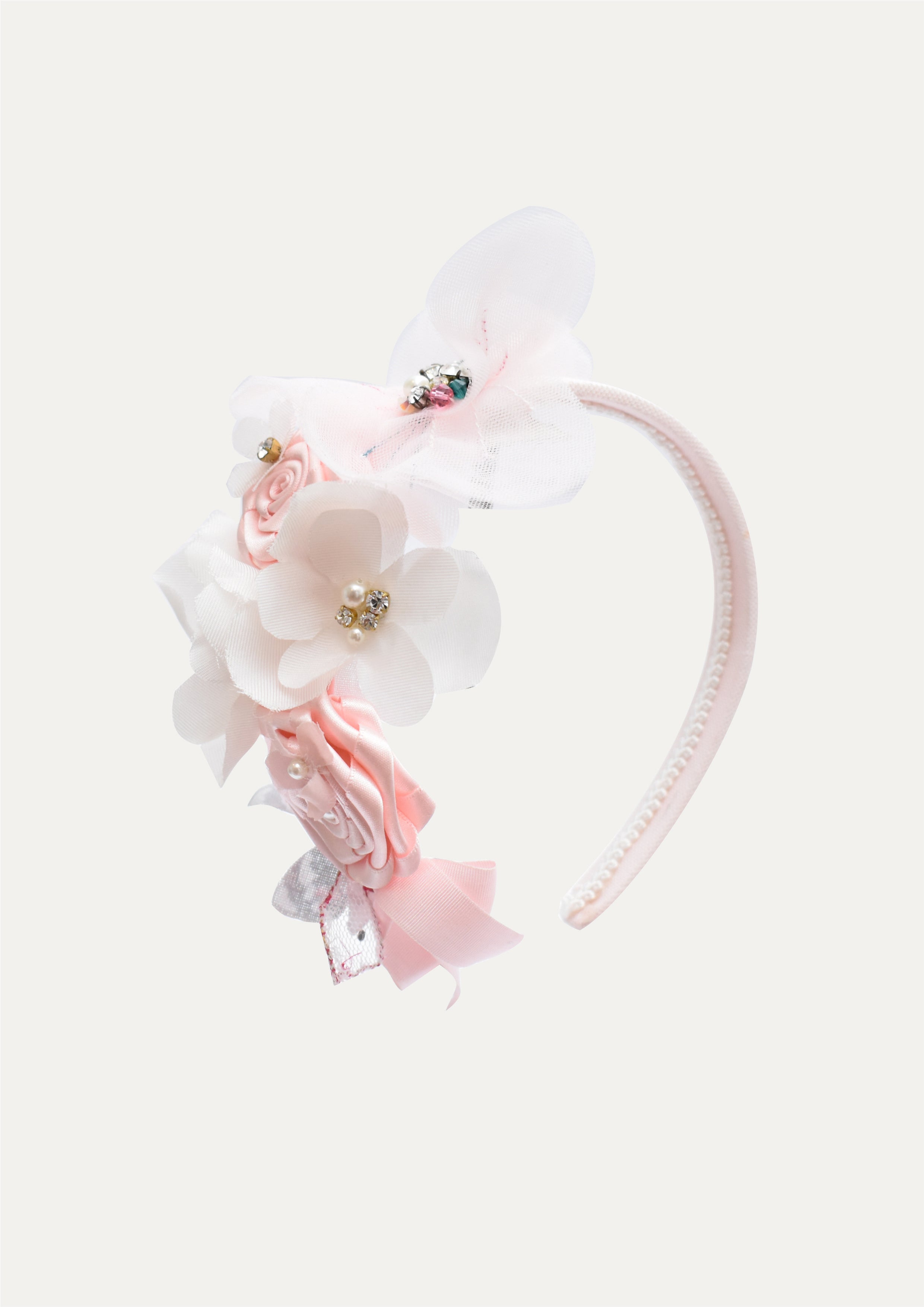 Handmade luxury headband for girls with an arrangement of pink satin roses, white chiffon flowers, pearls, and crystals, isolated on white background.