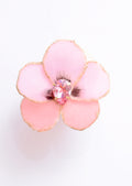 Close-up of a handmade pink fabric flower hair clip with gold edges and a sparkling pink teardrop crystal in the center.