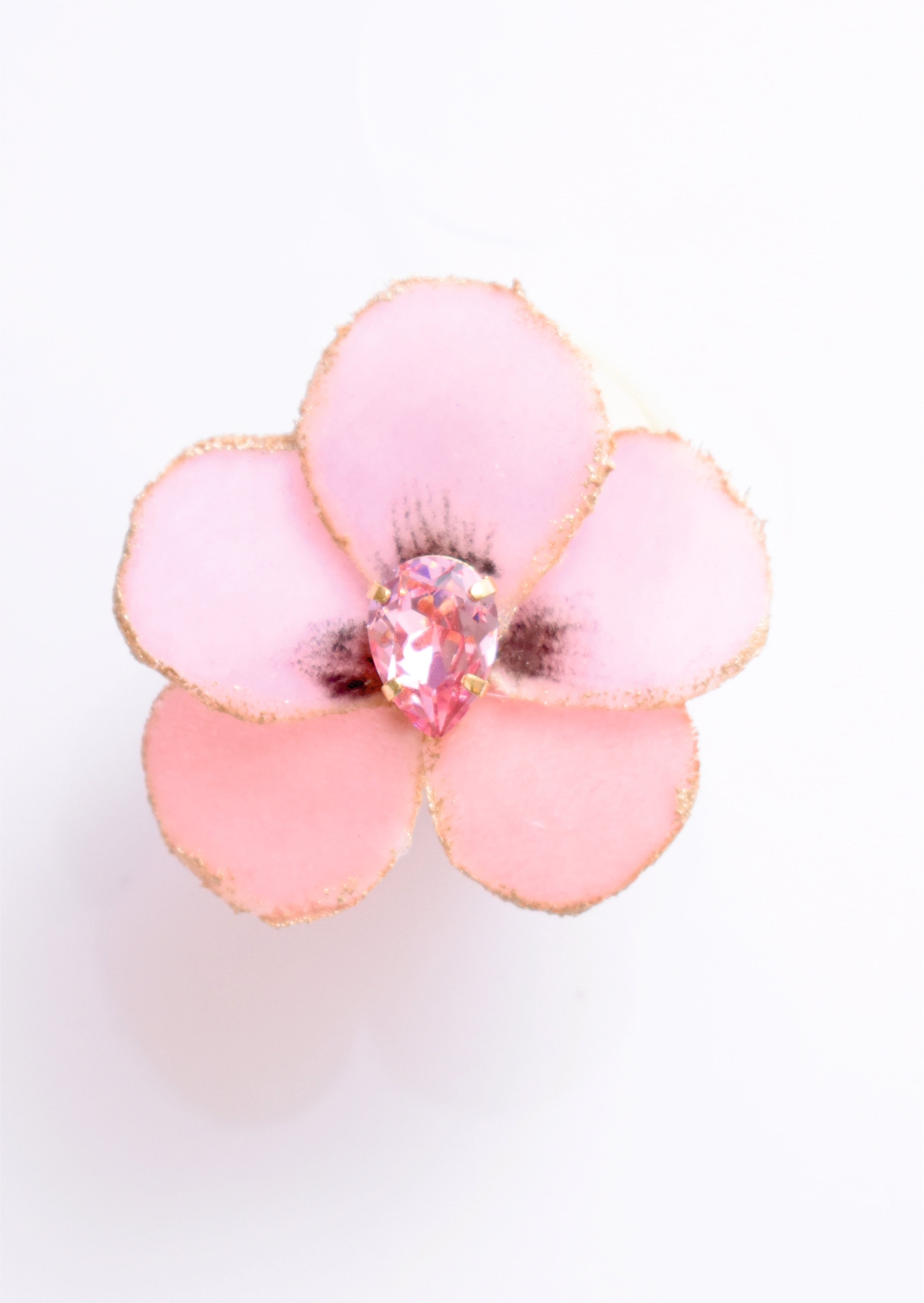Close-up of a handmade pink fabric flower hair clip with gold edges and a sparkling pink teardrop crystal in the center.