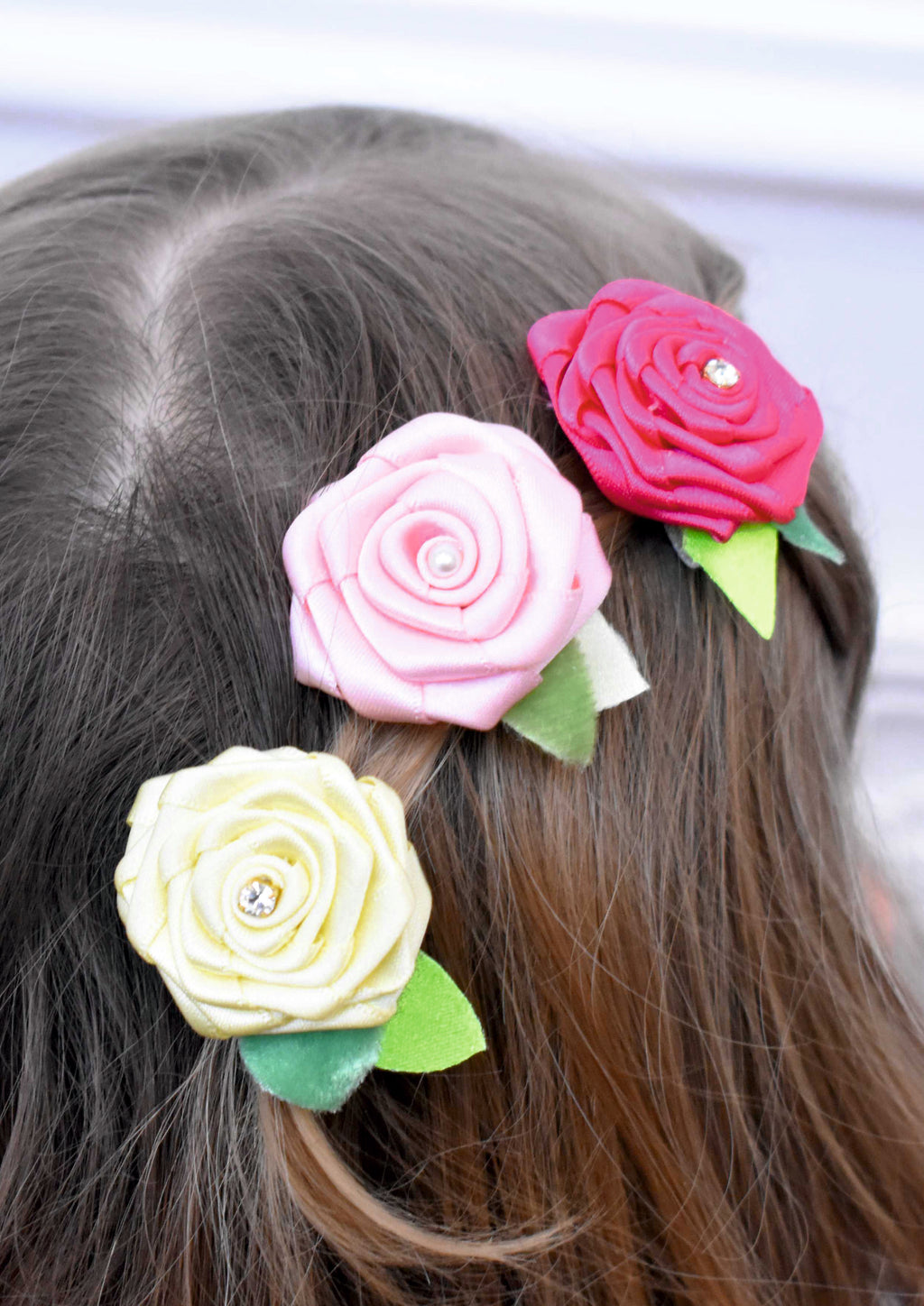 Detailed view of a handmade pink fabric flower hair clip featuring gold-edged petals and a large pink teardrop crystal in the center.