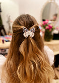 Detailed handmade butterfly hair clip with realistic wing patterns and sparkling crystal embellishments, worn in a woman's wavy brown half-up hairstyle.
